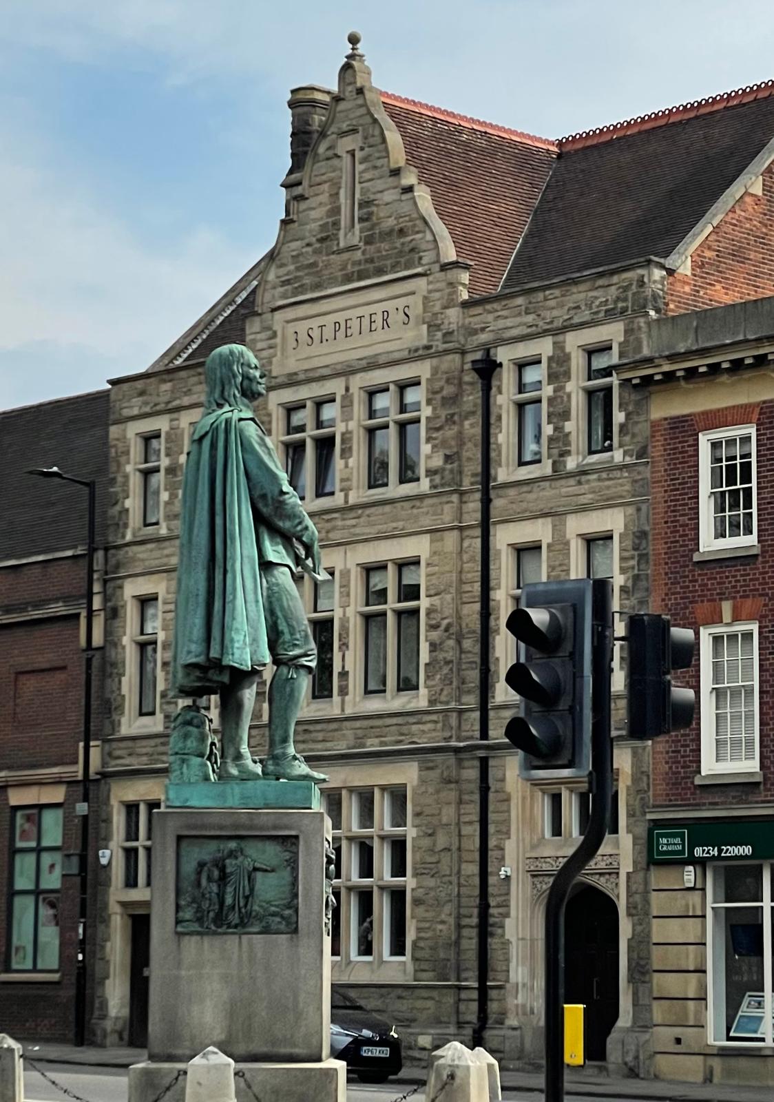 The John Bunyan statue with 3 St Peter's in the background